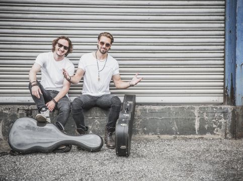 Das Duo „TwoForTwelve“ sitzt vor einer Garage