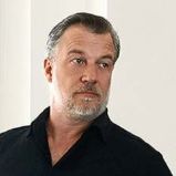 Ein schwarzgekleideter Mann mit weißen Schuhen steht vor einem Flügel