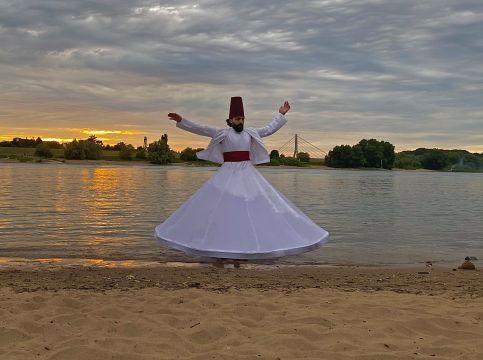 Tänzer in weitem weißen Gewand am Seeufer